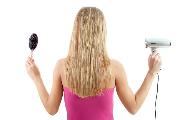 Blonde woman holding hairbrush and hairdryer