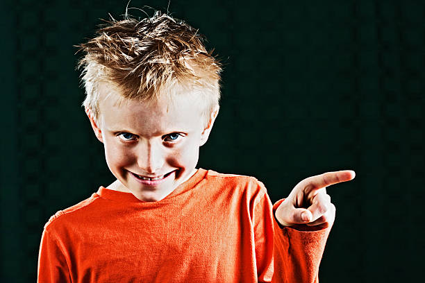 istock Naughty little boy smiles mischievously and points at something 175532626