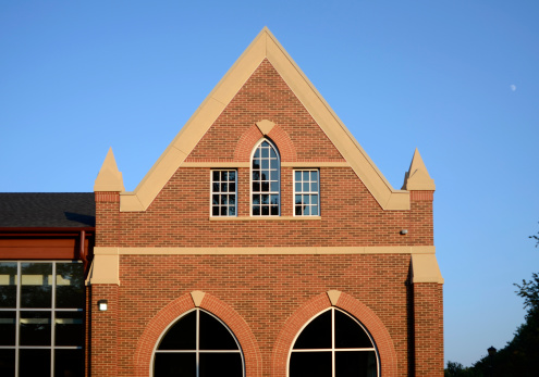 Detail of a contemporary, Gothic-style building against a blue sky at sunset.