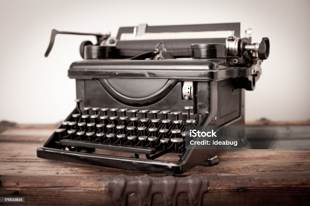 Vintage Black, Manual Typewriter, on White Background "Color image of vintage black, manual typewriter, sitting on wood trunk, on white background." Antique Stock Photo