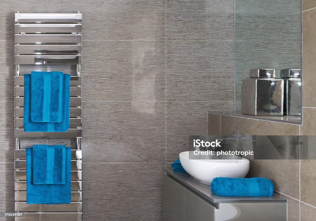 towel radiator and bathroom a chrome towel radiator with blue towels in a bathroom of a new home with a white porcelain basin and modern taps sitting on a cabinet beneath a mirror with a large chromed decorative jar on the shelf. Looking for a Bathroom image Then please see my other Bathrooms and related inages by clicking on the Lightbox link below...A>AA>A Towel Rail Stock Photo