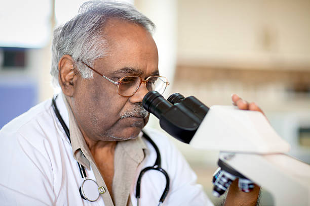 docteur indien à la recherche au microscope en laboratoire - male magnifying glass caucasian technician photos et images de collection