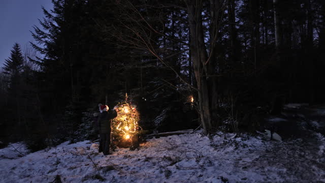 Teenagers decorating a Christmas tree in the forest