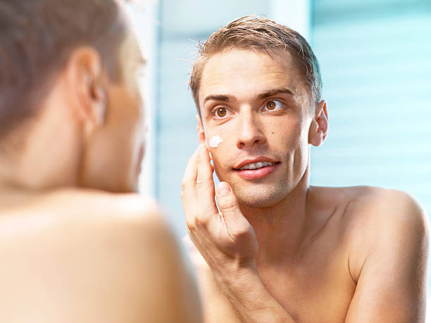 istock young man applying a face cream front of the mirror 175534869