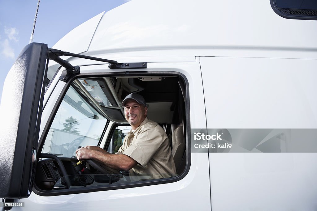 Truck driver sitting in cab of semi-truck Truck driver (30s) sitting in cab of semi-truck. Truck Driver Stock Photo