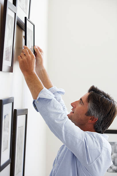 istock Man Hanging Picture Frames On Wall At Home 175535709
