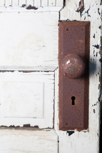Old rusty door knob on worn door
