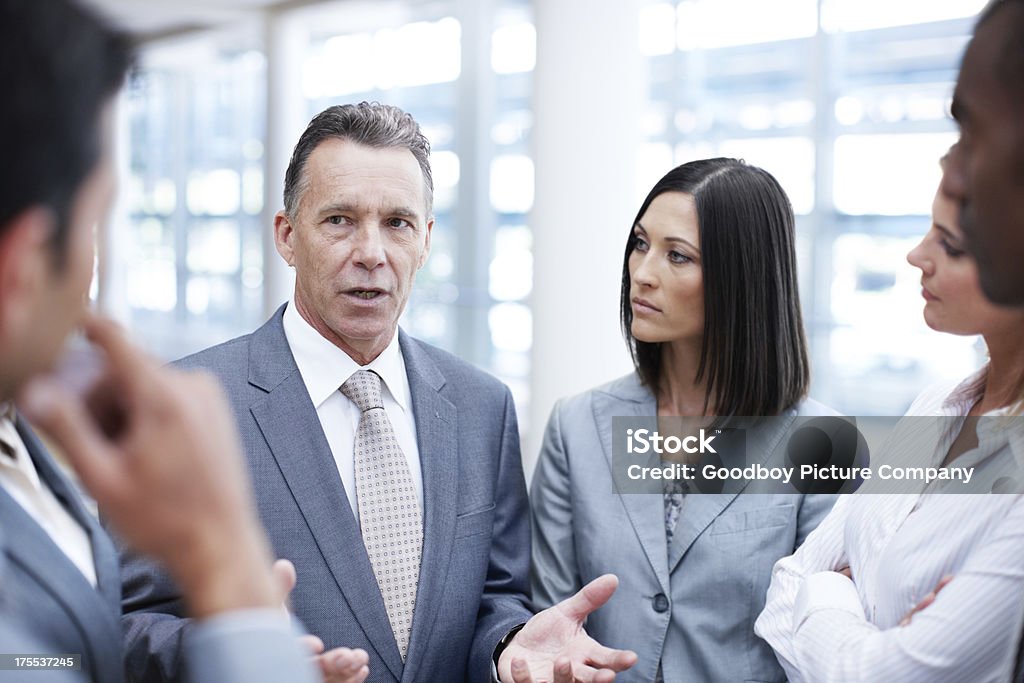 He's a focused businessman Senior businessman deep in discussion with his team Active Seniors Stock Photo