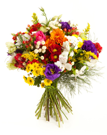 Bouquet of flowers with ocher daisies and gerberas in a vase with water and neutral background on white wooden table