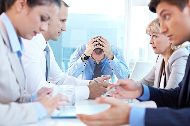 Boss in despair Stressed leader sitting at the head of table at staff meeting head in hands photos stock pictures, royalty-free photos & images