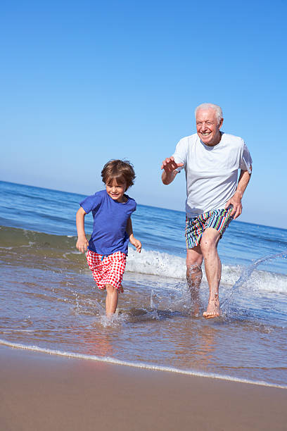 istock Grandfather Chasing Grandson Along Beach 175537869