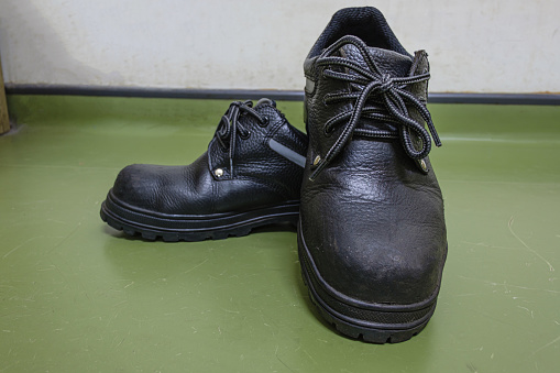 Safety shoes, leather, steel head  on a green background , Work shoes for men in factory or industry to protect foot from accident.