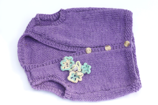 Purple waistcoat hand knitted with a flower decoration on a white background