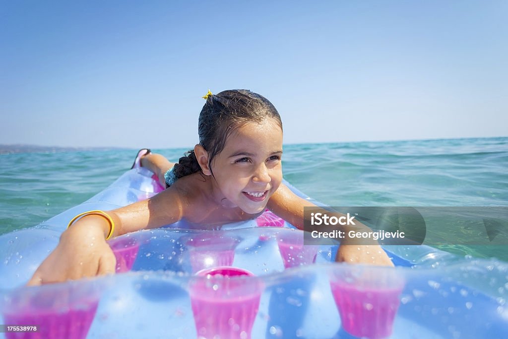 Dziewczynka w morze leżeć na plaży materaca - Zbiór zdjęć royalty-free (Beztroski)