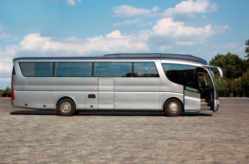 Silver coach with open door on a cobblestone.