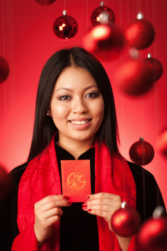Subject: An Asian Chinese model in traditional Asian dress suit holding luck money gift of red envelope posing for Chinese New Year celebration.