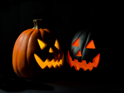 Two Jack O' Lanterns in the dark of night with copy space on a black background.