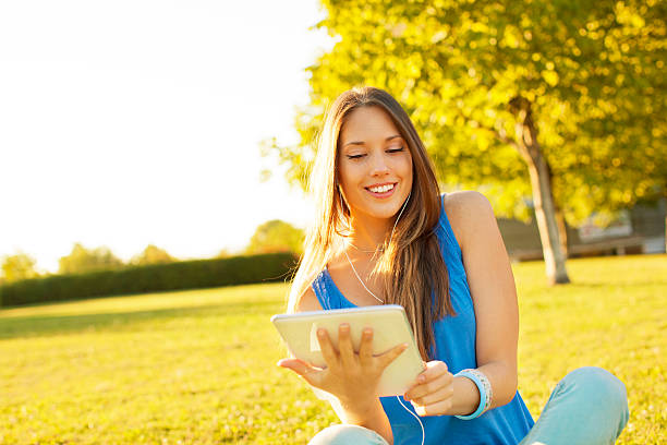 istock Happy Young Woman sitting on grass and using digital tablet. 175539612
