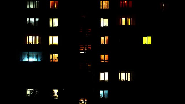 Turning on Light of many window of a house with many rooms at dark night. Group of Luminous Window in a big house or building