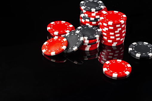 Red and black poker chips on black background close up