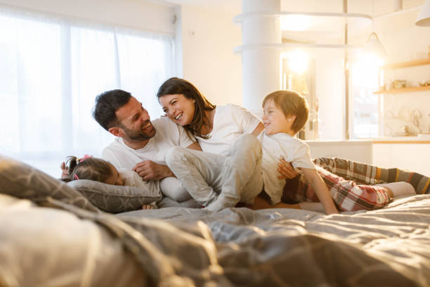 Cheerful parents and their kids having fun on a bed.