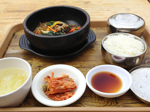 Traditional korean stew in a black frying pan and rice and soup and kimchi and soy sauce
