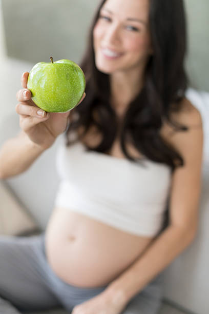 Heathy food for my baby. Pregnant woman holding a plate with fruits, studio isolated