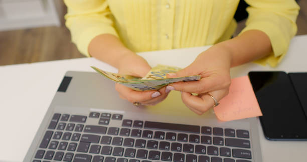istock Woman counting money over a laptop keyboard. 1755438042