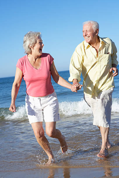 istock Senior Couple Running Along Beach Together 175544020