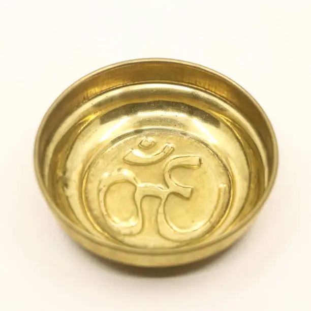 Photo of a golden prayer bowl with an antique hindu om symbol