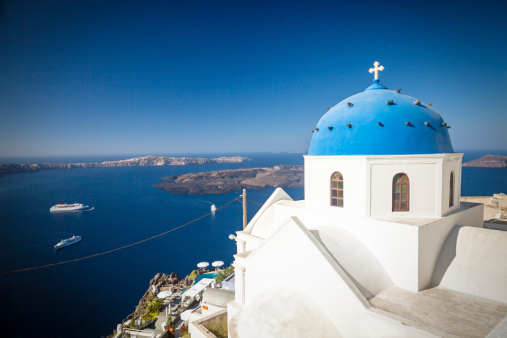 Church in Imerovigli, Santorini/Greece. Blue dome in front of a deep blue sky, caldera in the background.