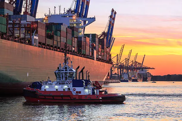 Hamburg Cargo terminal at sunset.A tug maneuvers a big container ship to the terminal.Taken with: Canon EOS 5D Mark 3 / 100mm 2.8L IS Macro