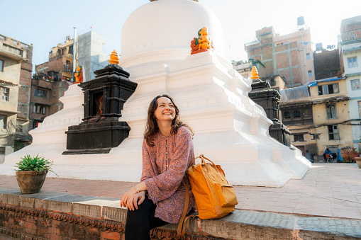 Woman sitting on the background of white stupa in Kathmandu, Nepal