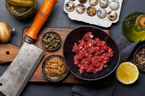 Cooking savory beef tartare with pickled gherkins and brown bread toasts. Flat lay