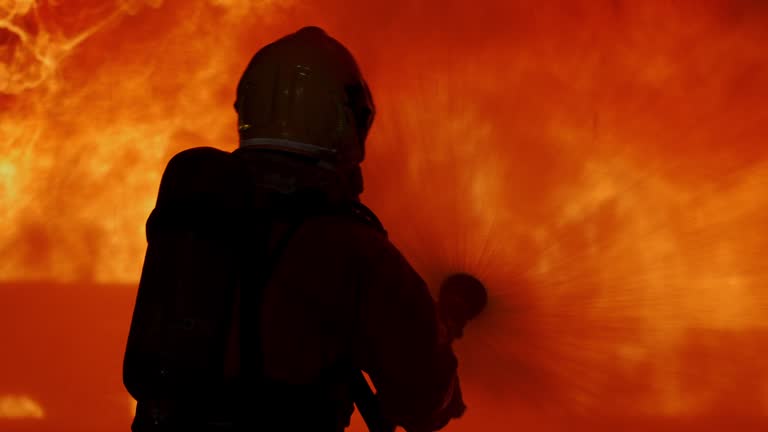 Firefighters holding hose and spraying water