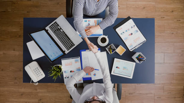 istock Top view of businesswomen shaking hands before analyzing management statistics paperwork 1755458500