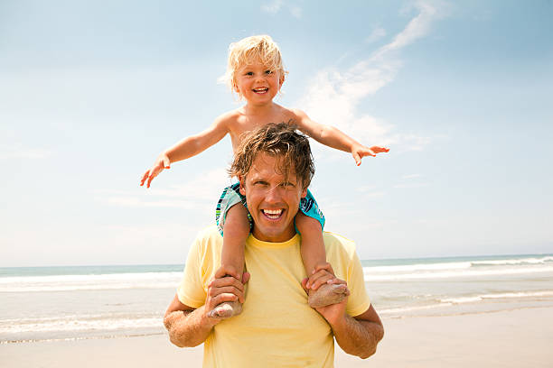 Cheerful father playing with his young son at the beach.