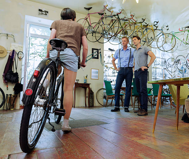 Small business owner showing a customers an antique bike. woman is getting ready to test ride a bike. Horizontal