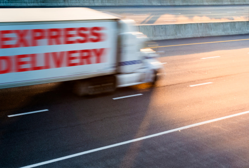 Fast moving delivery truck on highway at dusk