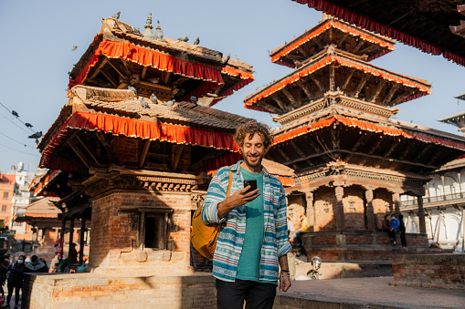 Man taking photos on smartphone while exploring   Bhaktapur Durbar square in Kathmandu