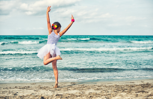 Little girl dancing ballet on the beach.