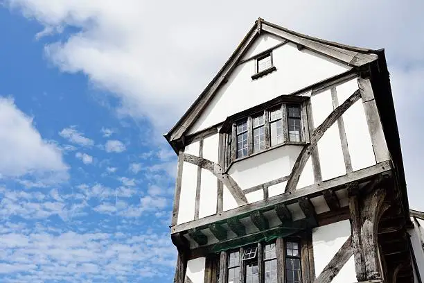 A half-timbered Tudor style building against a blue sky with white clouds in Exeter, Devon, England.