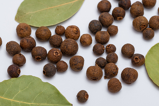Bay leaves and allspice arranged on a white background closeup