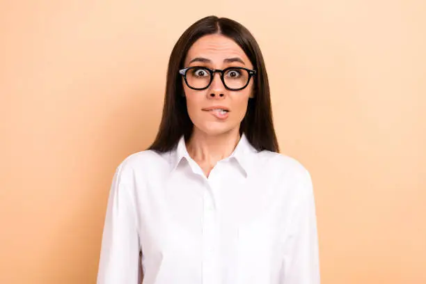 Photo of Portrait of young funny astonished nervous girl worried bite lips first business meeting find new job isolated on beige color background