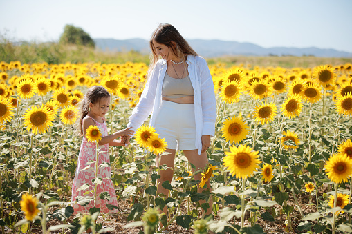 Happy mother with the daughter in the field with sunflowers. mom and baby girl having fun outdoors. family concept.