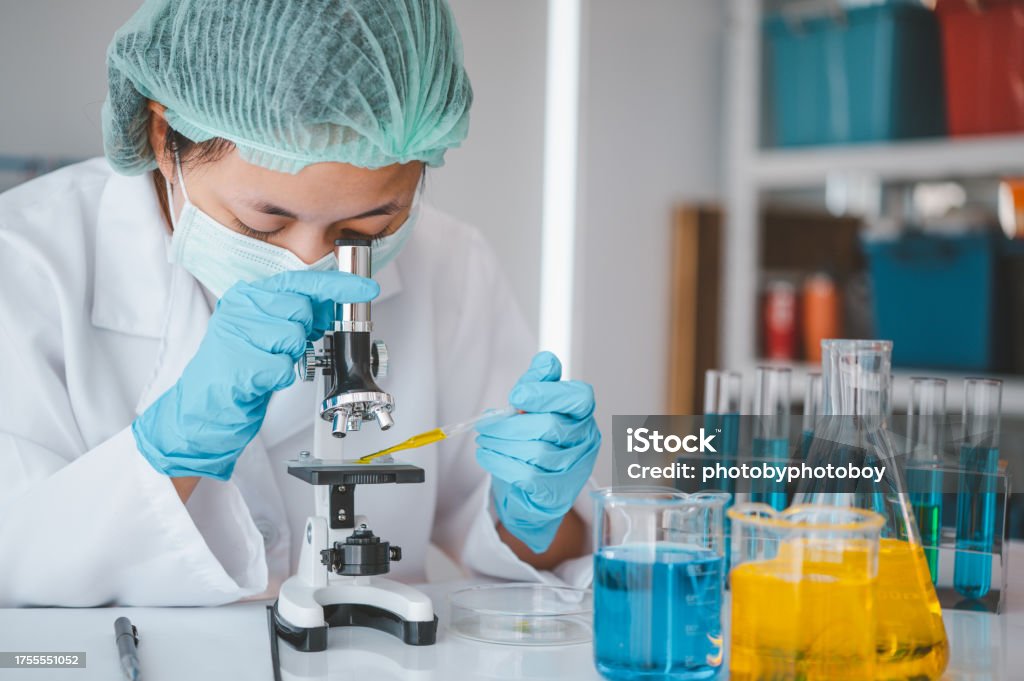 Female researchers are experimenting with pipette dropping a sample into a test tube in an experiment research in laboratory.. Analyzing Stock Photo