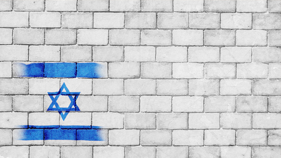 A very light grey white colored brick wall with rectangular blocks, textured grungy backgrounds with vibrant contrasting Israeli flag painted over dull faint neutral backdrop. There is no people and copy space. It is a rustic modern backdrop template.