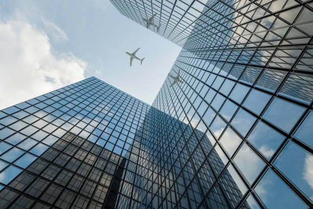 istock Skyscraper with Glass Curtain Wall, Reflecting Sky and Clouds, as an Airplane Passes By 1755571371