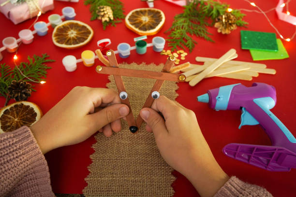 istock Step by step instruction how to make christmas deer from ice cream sticks. Step 5 Child's holding finished New year handmade craft deer Children's New year handmade craft 1755571388