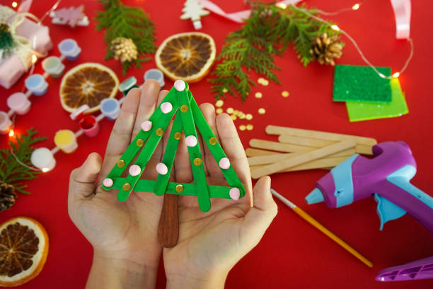 istock Step by step instruction how to make christmas tree from ice cream sticks. Step 4 Child's holding finished New year handmade craft tree. Concept of DIY and kid's creativity. 1755571783